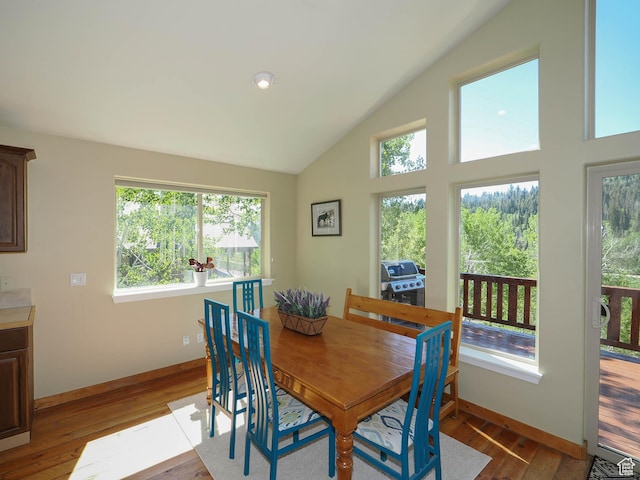 dining area with high vaulted ceiling, baseboards, and hardwood / wood-style floors