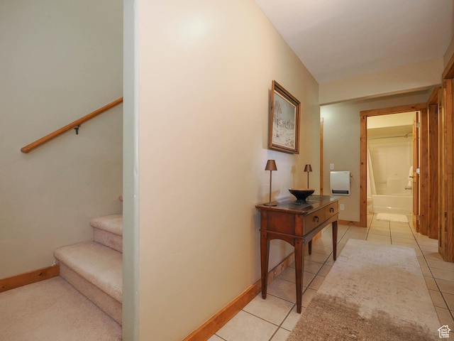 hall featuring baseboards, stairway, and light tile patterned flooring