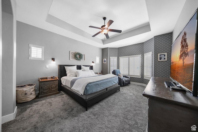 bedroom with carpet floors, baseboards, and a raised ceiling