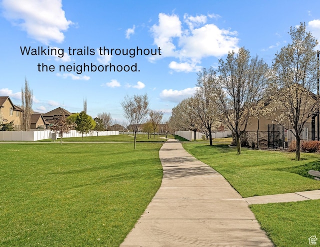 view of community with fence, a residential view, and a lawn