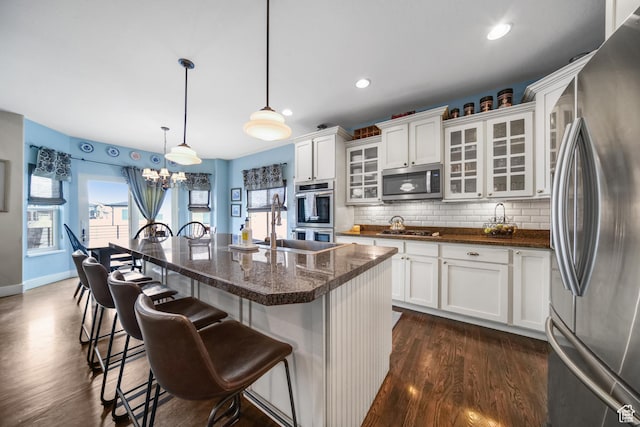 kitchen with tasteful backsplash, dark wood-style flooring, white cabinetry, a breakfast bar area, and appliances with stainless steel finishes