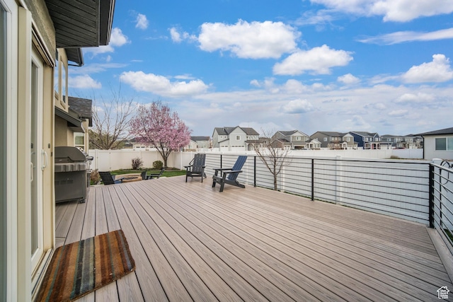 wooden deck with a residential view, a grill, and fence