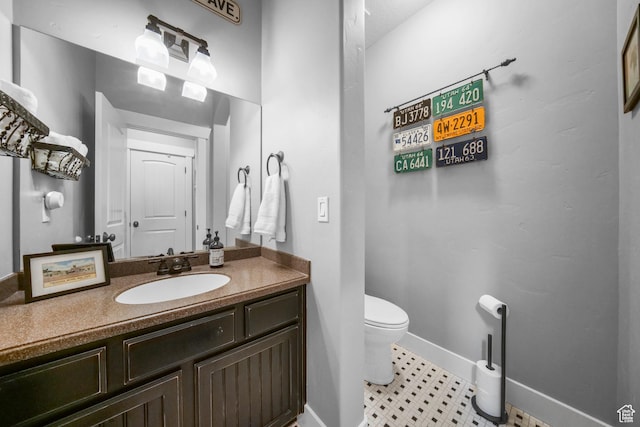 half bath with toilet, vanity, and baseboards