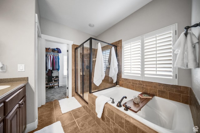 bathroom with vanity, a spacious closet, a stall shower, and a garden tub