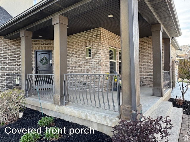 doorway to property featuring brick siding and covered porch