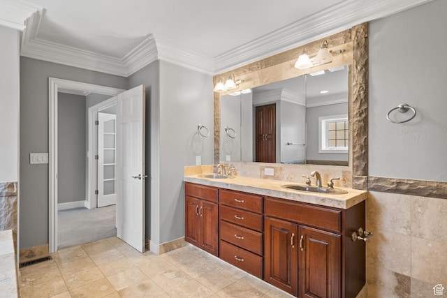 bathroom featuring double vanity, visible vents, a sink, and ornamental molding
