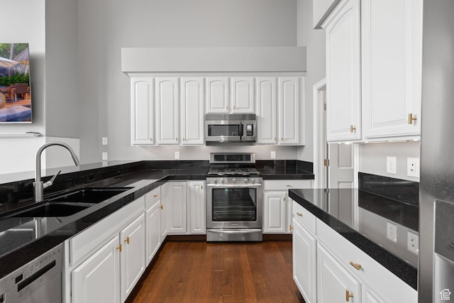 kitchen featuring appliances with stainless steel finishes, a sink, dark wood-style floors, and white cabinets
