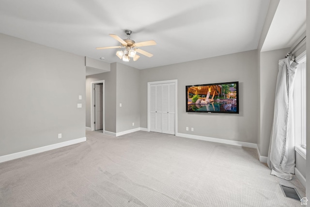 empty room featuring light colored carpet, ceiling fan, baseboards, and visible vents