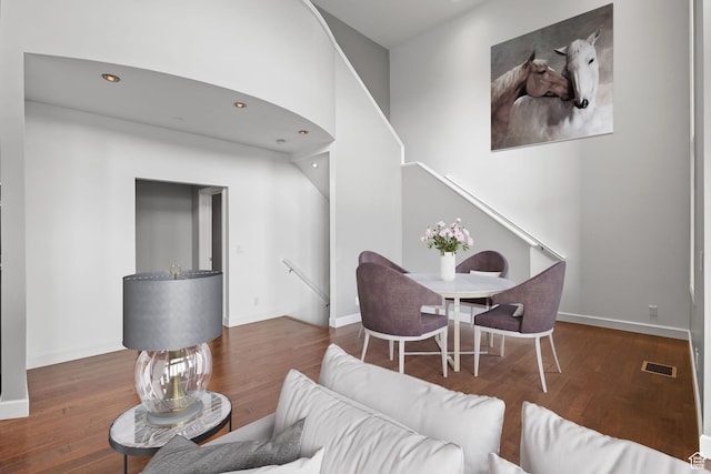living area with stairs, visible vents, baseboards, and wood finished floors