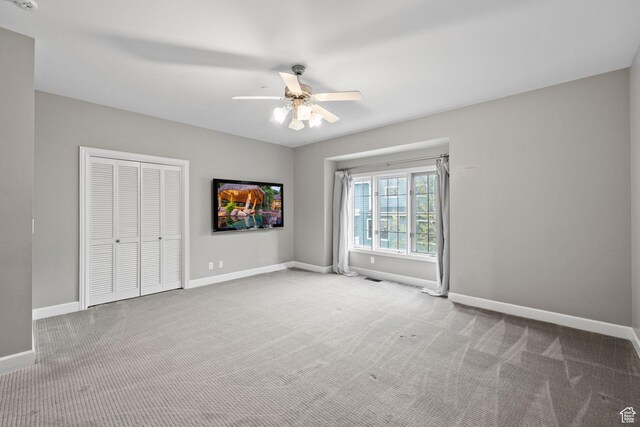 unfurnished bedroom with a closet, baseboards, carpet flooring, visible vents, and ceiling fan