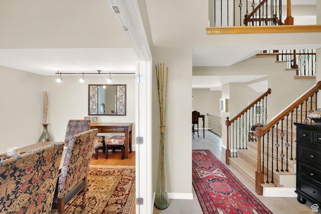 entryway with baseboards, stairway, and rail lighting