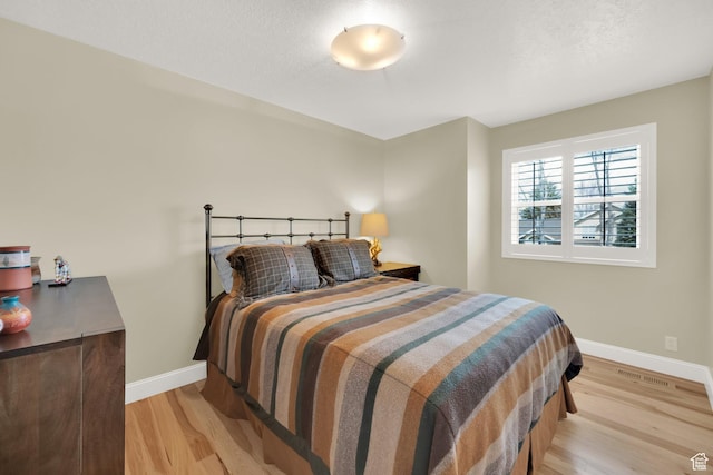 bedroom with baseboards and light wood finished floors