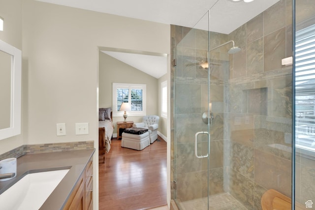 ensuite bathroom featuring vanity, vaulted ceiling, a stall shower, ensuite bath, and wood finished floors