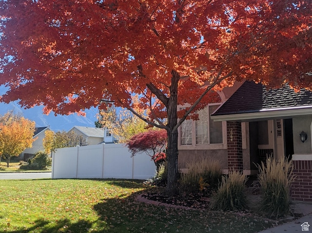 view of home's exterior with stucco siding, fence, and a lawn