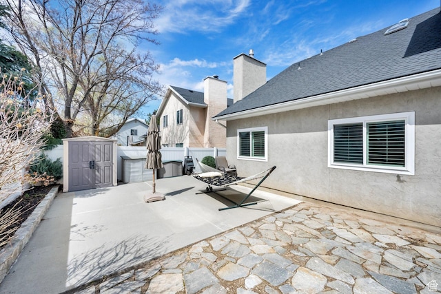 view of patio / terrace featuring an outbuilding, a storage unit, and fence
