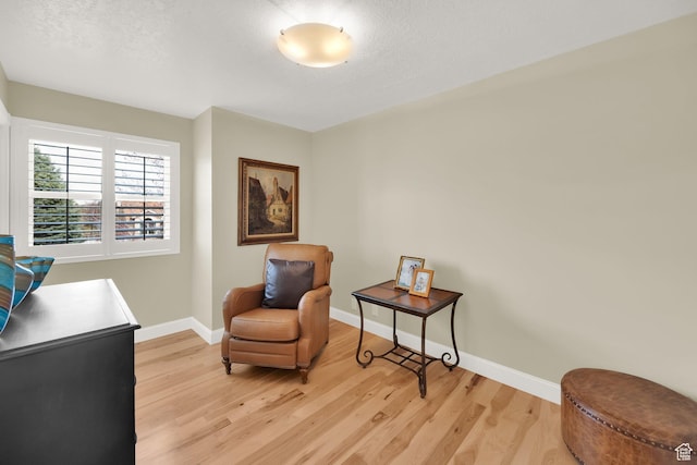 living area featuring light wood-style floors, baseboards, and a textured ceiling