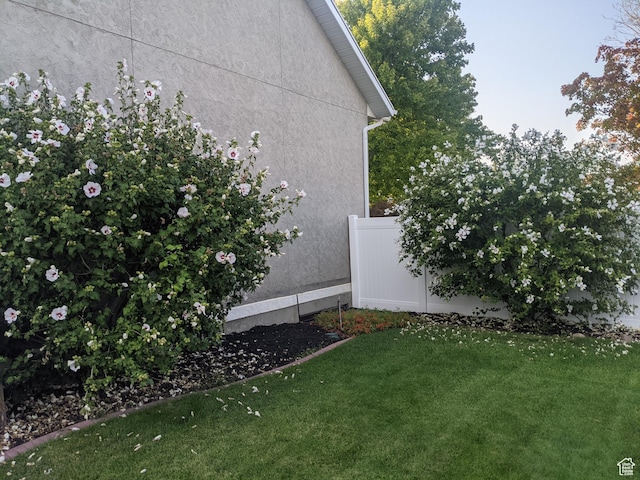 view of property exterior featuring a yard, stucco siding, and fence
