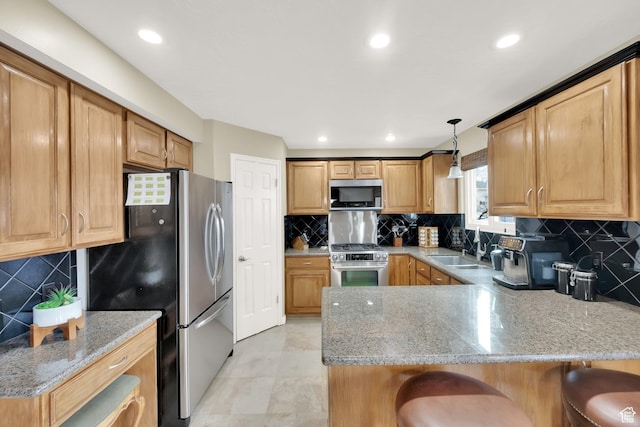 kitchen with a kitchen bar, a peninsula, light stone counters, a sink, and stainless steel appliances