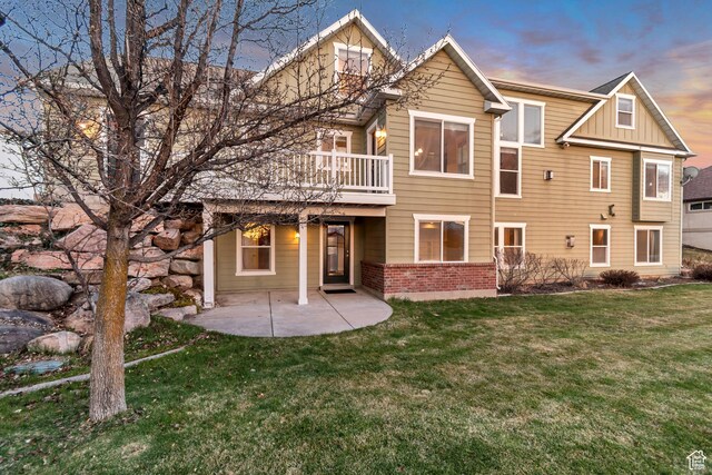 1135 Grandview Dr, Providence, UT 84332 - back of house at dusk featuring board and batten siding, a patio, brick siding, and a lawn