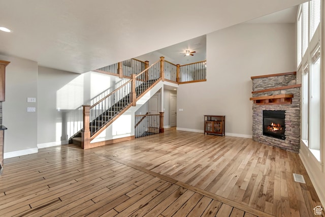 1135 Grandview Dr, Providence, UT 84332 - unfurnished living room featuring hardwood / wood-style flooring, a stone fireplace, stairway, plenty of natural light, and a towering ceiling