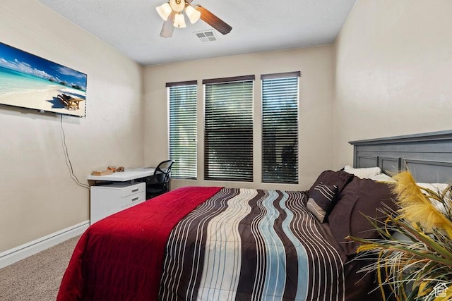 carpeted bedroom with visible vents, baseboards, and a ceiling fan