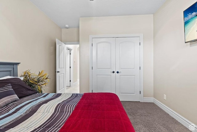 carpeted bedroom featuring a closet and baseboards