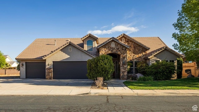 view of front facade with a tiled roof, a garage, stucco siding, stone siding, and concrete driveway