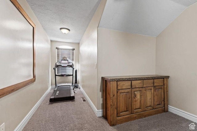 hallway featuring carpet floors, baseboards, visible vents, and a textured ceiling