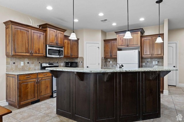 kitchen with stainless steel appliances, visible vents, brown cabinetry, and a center island with sink