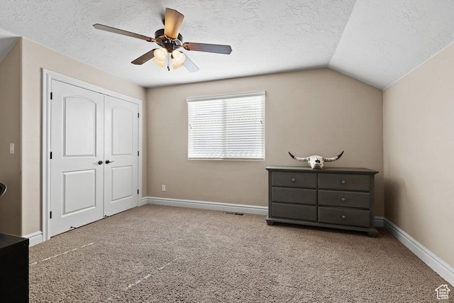 carpeted bedroom with a textured ceiling, a closet, baseboards, and lofted ceiling