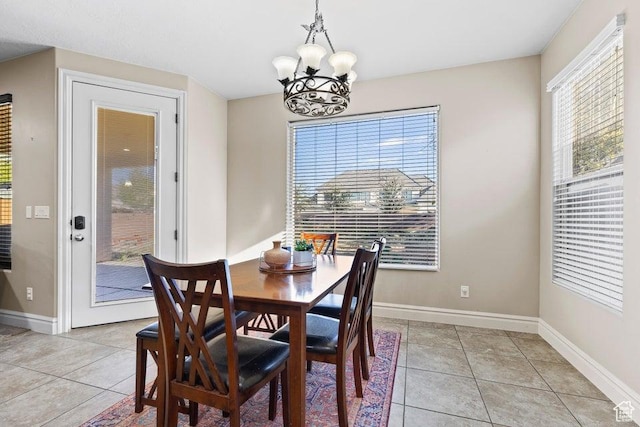 dining space featuring baseboards, an inviting chandelier, and light tile patterned flooring