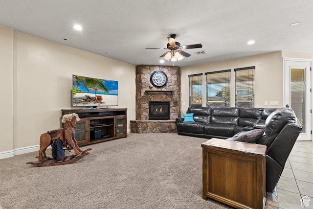 living room featuring visible vents, ceiling fan, a textured ceiling, a fireplace, and light colored carpet