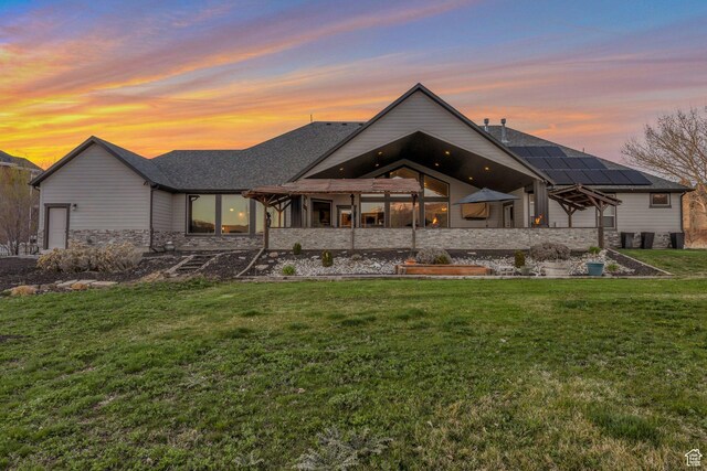 1737 E 6850 S, Uintah, UT 84405 - back of property at dusk featuring stone siding, a yard, and roof with shingles
