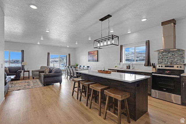 140 W 150 S Unit 22, Garden City, UT 84028 - kitchen featuring stainless steel electric range oven, island exhaust hood, a sink, a center island, and a breakfast bar area