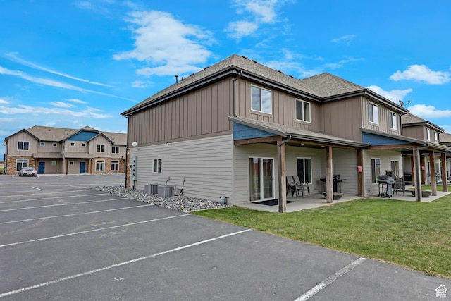 140 W 150 S Unit 22, Garden City, UT 84028 - back of property featuring board and batten siding, uncovered parking, a lawn, central AC unit, and a patio area