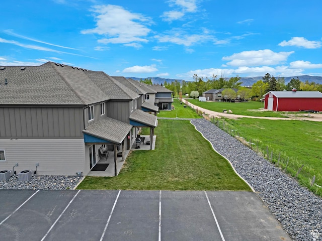 140 W 150 S Unit 22, Garden City, UT 84028 - view of property exterior featuring a mountain view, uncovered parking, a shingled roof, a patio area, and a yard
