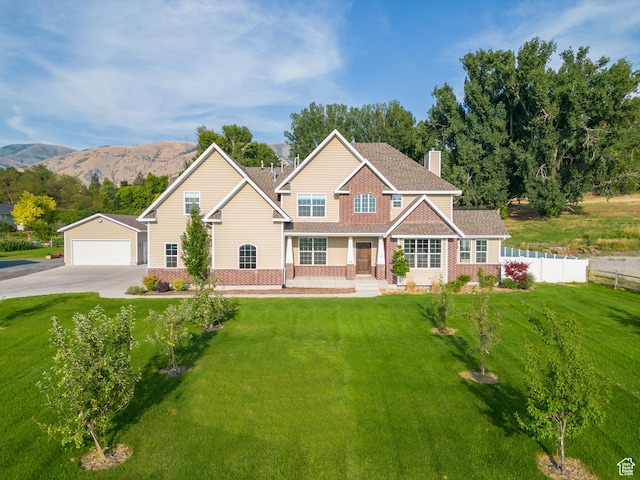 view of front of property featuring a front yard, a mountain view, fence, and brick siding