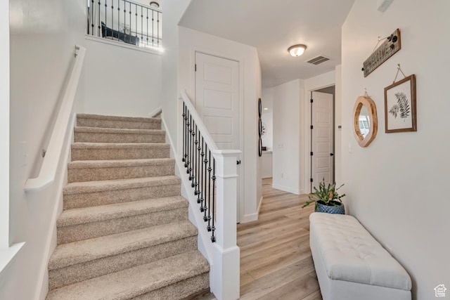 stairs with visible vents, baseboards, and wood finished floors