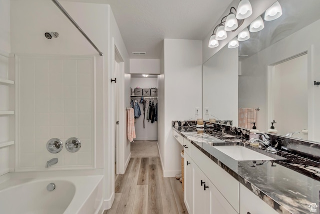 bathroom featuring bathing tub / shower combination, vanity, visible vents, wood finished floors, and a walk in closet