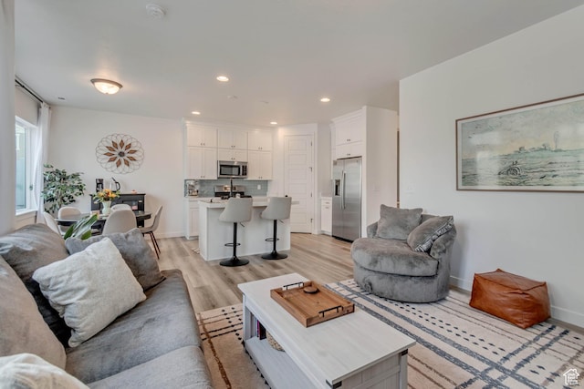 living area with light wood-style flooring, recessed lighting, and baseboards