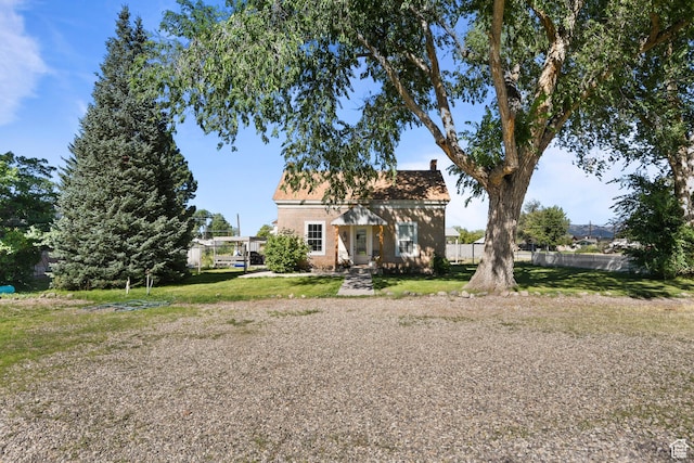 view of front of property with brick siding, a front yard, and fence
