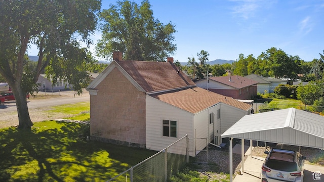 exterior space with a yard, a carport, fence, a chimney, and driveway