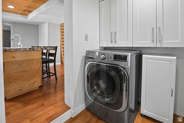 laundry room featuring laundry area, wood finished floors, a sink, washer / dryer, and baseboards