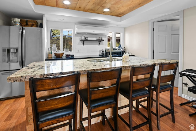 kitchen featuring wooden ceiling, stainless steel refrigerator with ice dispenser, a wall mounted air conditioner, a tray ceiling, and light wood-style flooring