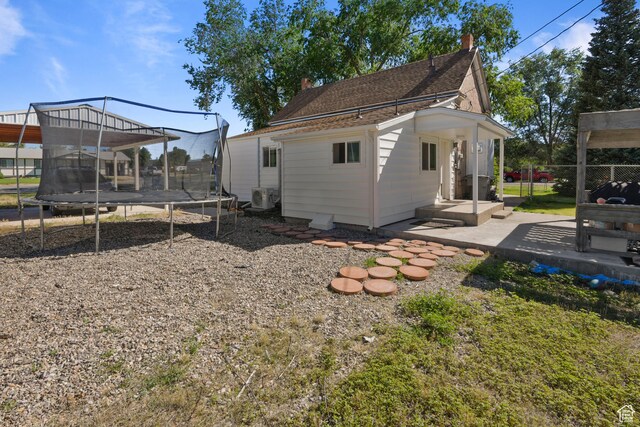 back of house with a trampoline, a patio area, and a chimney