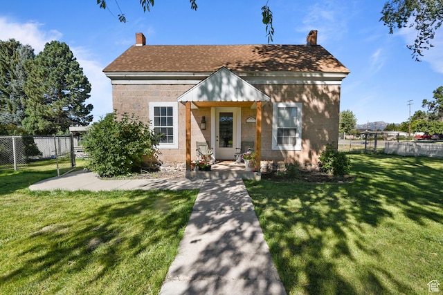 view of front of property with fence, a front yard, a chimney, and a shingled roof