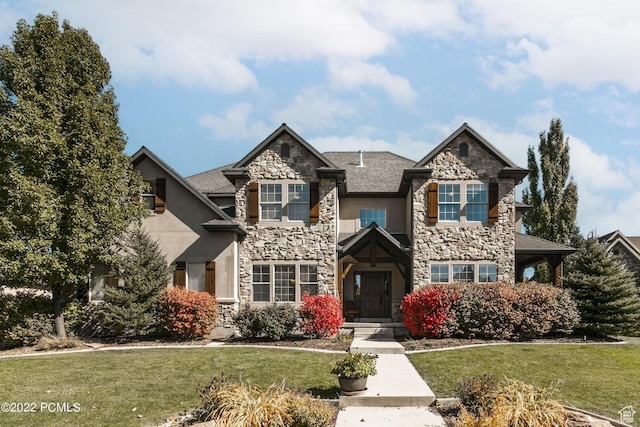 view of front of property with a front yard, stone siding, and stucco siding