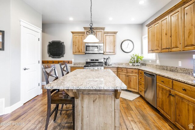 923 Ledgestone Ln, Heber City, UT 84032 - kitchen with a kitchen bar, a center island, light stone counters, stainless steel appliances, and light wood finished floors