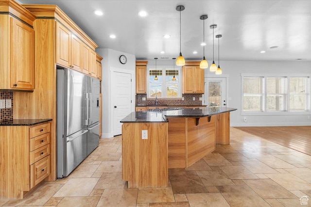 kitchen featuring stone tile flooring, high quality fridge, a center island, and decorative backsplash