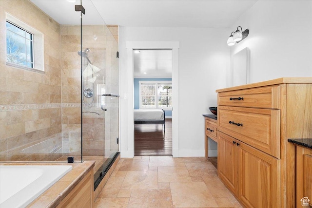 full bathroom with ensuite bathroom, stone tile floors, vanity, a stall shower, and baseboards